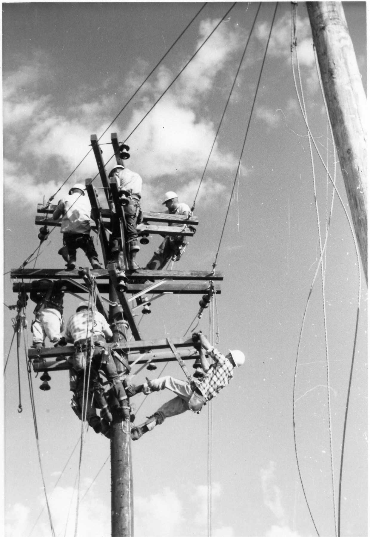 Seven linemen on top of a power pole