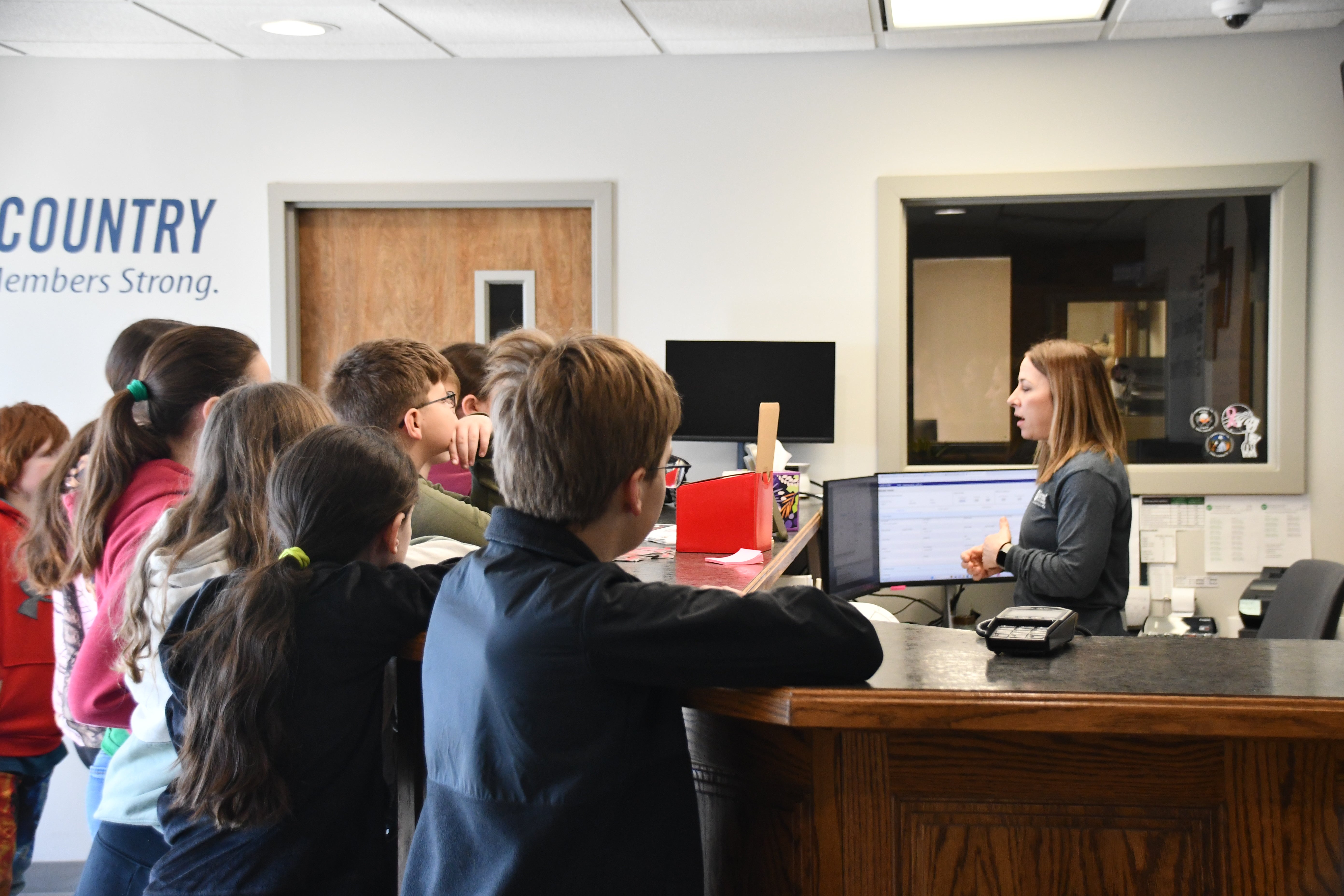 PIE students listening to FEC employee at front desk during office visit